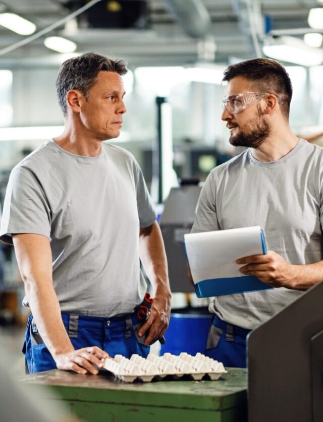 Een industriële medewerker raadpleegt zijn flexibele planning via een mobiele app op de werkvloer voor een betere werk-privébalans.